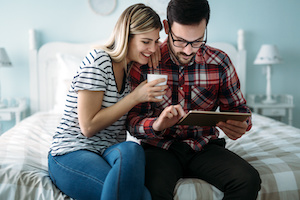 Young happy couple using digital tablet in bedroom